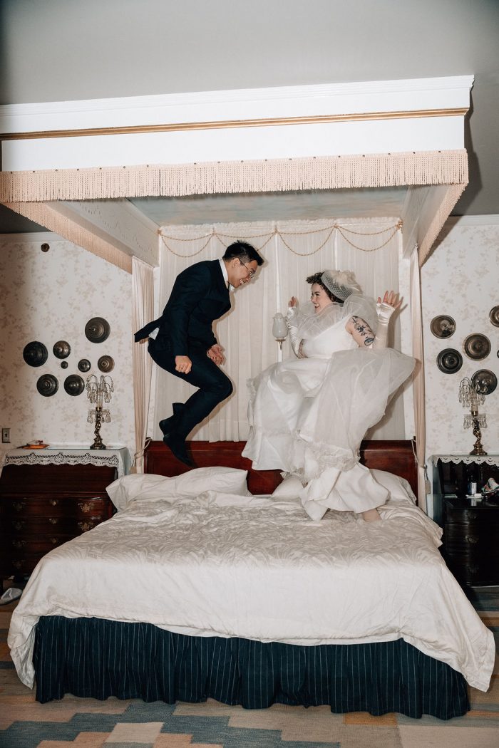 bride in vintage wedding dress jumping on bed