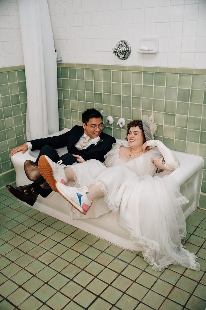 bride in vintage wedding dress sitting in bathtub 