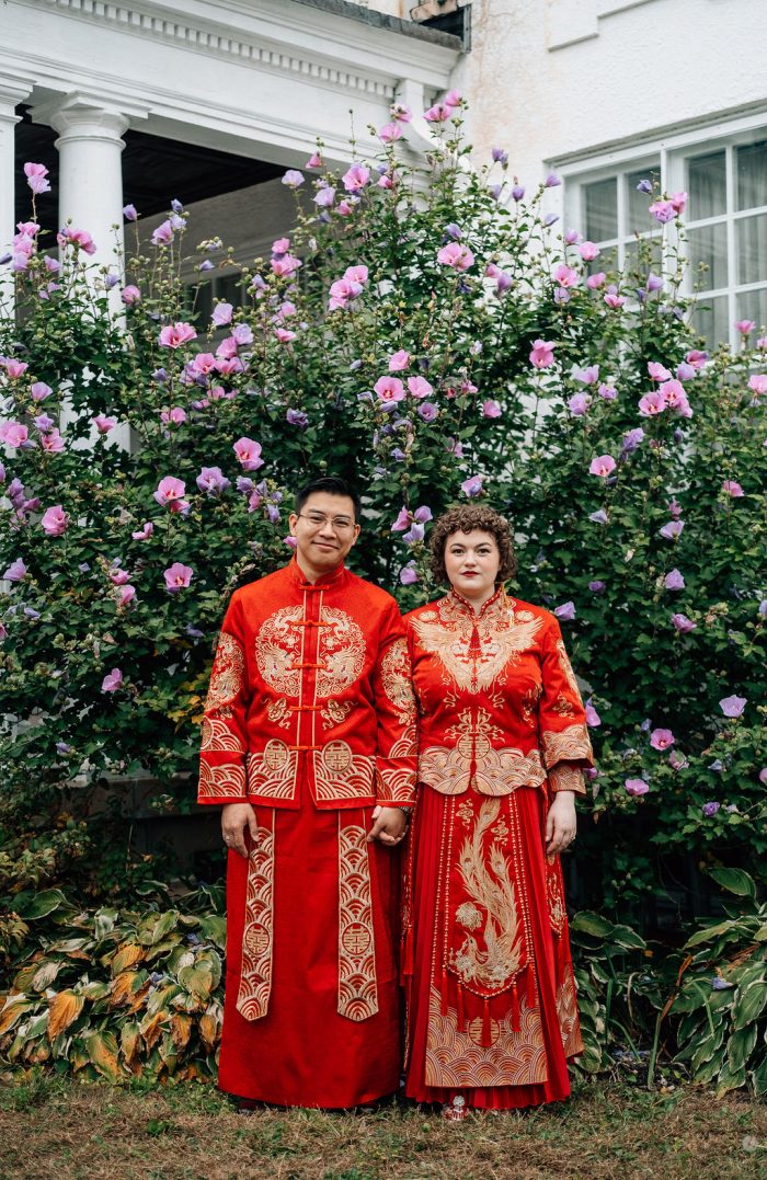 bride and groom in traditional chinese clothing in front of flowers